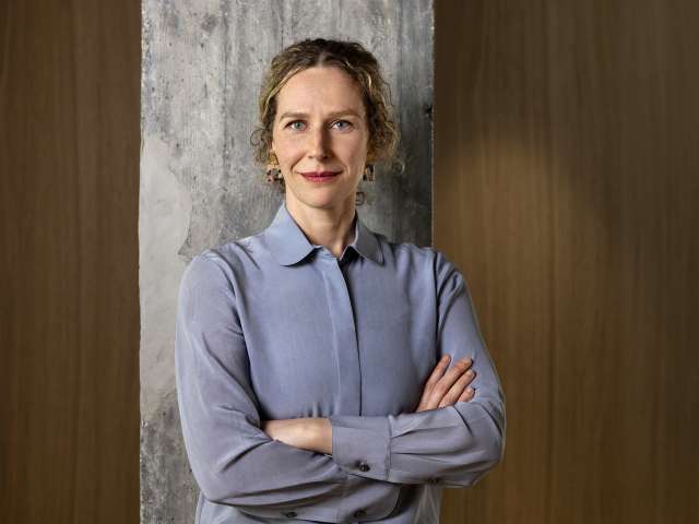Sabine Müller is standing in front of a wall, wearing a light blue shirt.